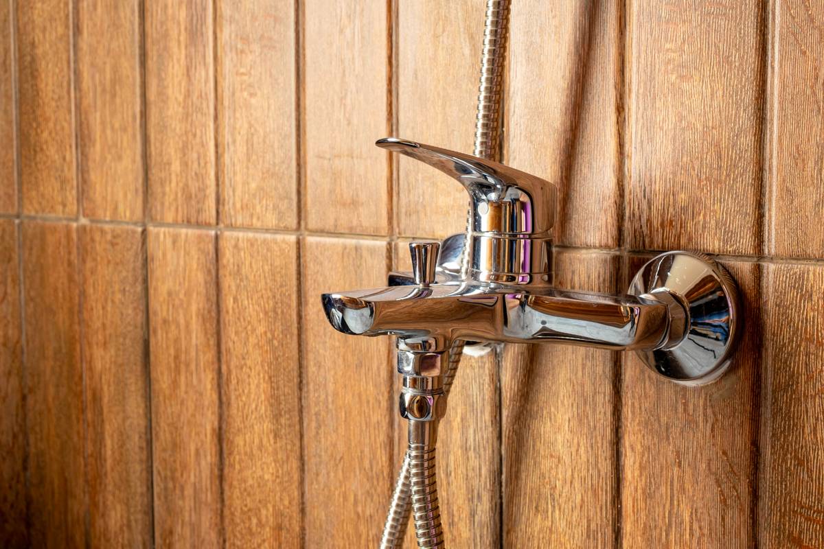 Diagram showing components of a bathroom fixture dual shower head handheld system: fixed overhead head, handheld wand, wall-mounted holder, diverter valve, and hose