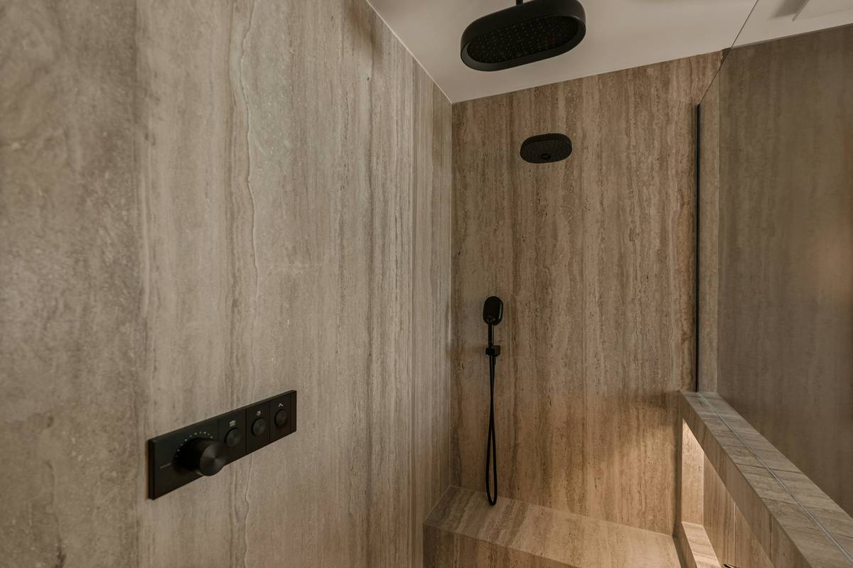 Modern bathroom featuring black dual shower heads mounted on wall with rainfall and handheld sprayers